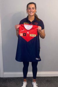 Aimee Mackin holding her Melbourne Demons AFLW guernsey